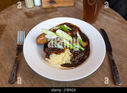 Assiette de pub anglais traditionnel aliments - Assiette de saucisses et purée à l'oignon jus de viande et une pinte de la real ale, UK Banque D'Images