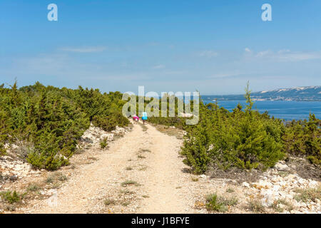 Les touristes à pied sur une route de gravier près de LUN, l''île de Pag, Croatie Banque D'Images