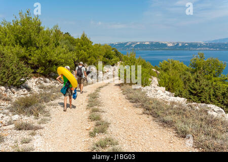 Les touristes à pied sur une route de gravier près de LUN, l''île de Pag, Croatie Banque D'Images