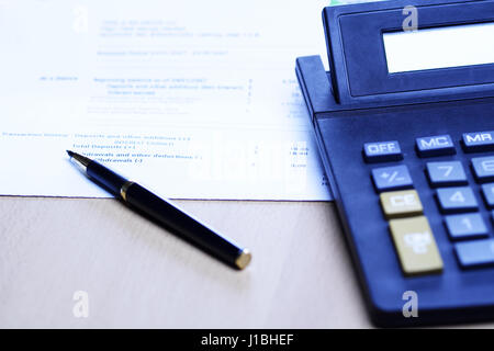 Une image d'un stylo et une calculatrice sur le dessus d'un état financier, peut être utilisée pour l'entreprise concept finance et comptabilité ( tourné en ton bleu) Banque D'Images