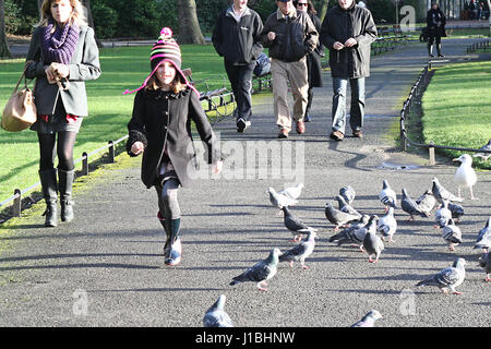 Jeune fille, enfant chassant les pigeons dans le parc St Stephen Green, Dublin, concept d'enfance fun parc liberté, meilleure vie, heureux de vivre, d'un mode de vie sain chase Banque D'Images