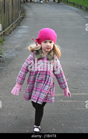 Petite fille enfant portant un chapeau rose et pollen chaud wolly co s'exécutant dans le St Stephen's Green Park. En hiver, portant un chapeau et manteau, Dublin Irlande Banque D'Images