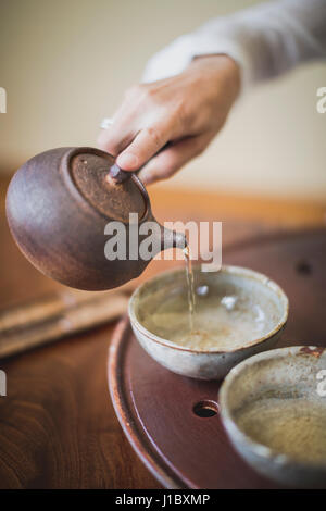 Sarah Hedden pouring tea en céramique tasses à thé sur un plateau. Banque D'Images