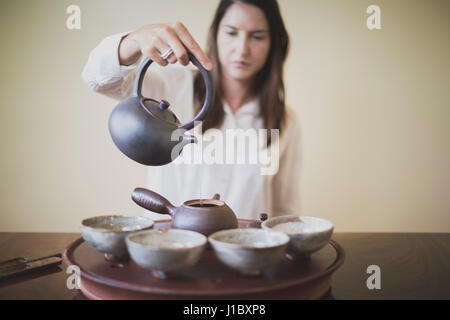 Sarah Hedden pouring tea en céramique tasses à thé sur un plateau. Banque D'Images