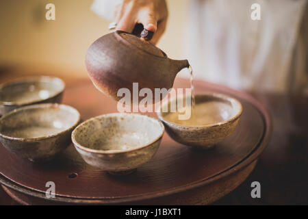 Sarah Hedden pouring tea en céramique tasses à thé sur un plateau. Banque D'Images