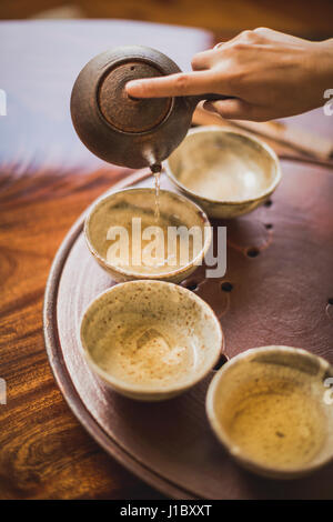 Sarah Hedden pouring tea en céramique tasses à thé sur un plateau. Banque D'Images