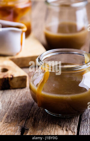 Sauce caramel fait maison dans un bocal en verre sur la table en bois rustique Banque D'Images