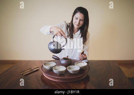 Sarah Hedden pouring tea en céramique tasses à thé sur un plateau. Banque D'Images