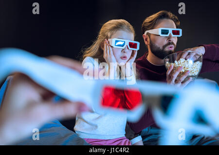 Choqué dans père et fille 3D glasses watching movie et eating popcorn Banque D'Images