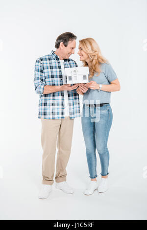 Vue avant de l'heureux couple holding house model on white Banque D'Images