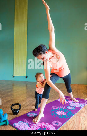 Mixed Race future mère pratiquant le yoga et en regardant sa fille Banque D'Images