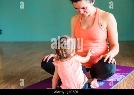 Mixed Race girl touching ventre de future maman, on exercise mat Banque D'Images