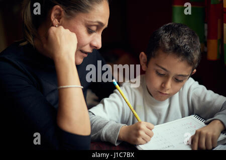 Mère hispaniques regardant fils pratiquer l'alphabet d'écriture Banque D'Images