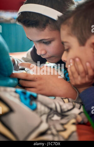 Frères hispaniques texting on cell phone Banque D'Images