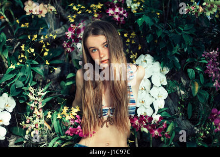 Caucasian woman wearing bikini assis dans les fleurs Banque D'Images