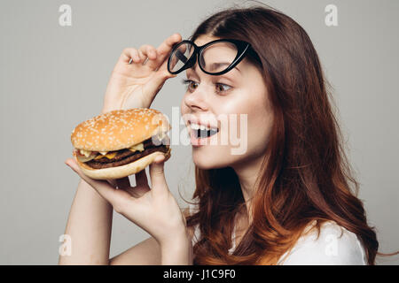 Lunettes de levage Caucasian woman looking at cheeseburger Banque D'Images