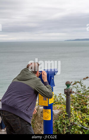 Un homme looking through telescope sur la mer,Devon ,Angleterre,UK Banque D'Images