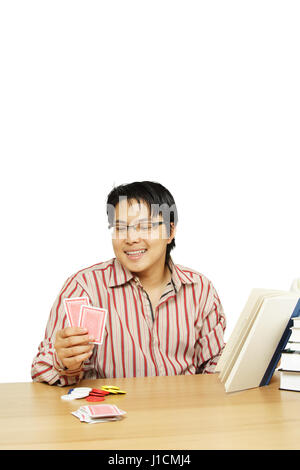 Un coup isolé d'un étudiant indécis entre cartes à jouer ou à étudier Banque D'Images