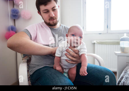 Jeune père de sa fille burping, tenant son affectueusement. Session familiale Lifestyle.. Banque D'Images