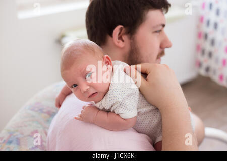 Jeune père de sa fille burping, tenant son affectueusement. Session familiale Lifestyle.. Banque D'Images