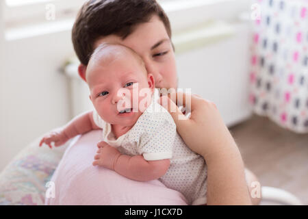 Jeune père de sa fille burping, tenant son affectueusement. Session familiale Lifestyle.. Banque D'Images