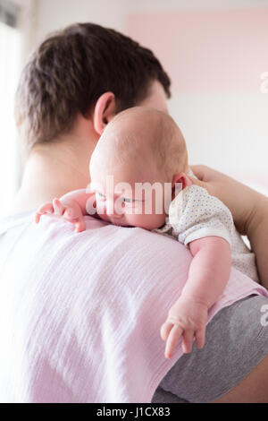 Jeune père de sa fille burping, tenant son affectueusement. Session familiale Lifestyle.. Banque D'Images