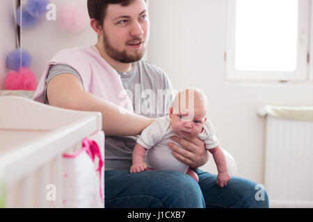 Jeune père de sa fille burping, tenant son affectueusement. Session familiale Lifestyle.. Banque D'Images