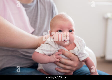 Jeune père de sa fille burping, tenant son affectueusement. Session familiale Lifestyle.. Banque D'Images