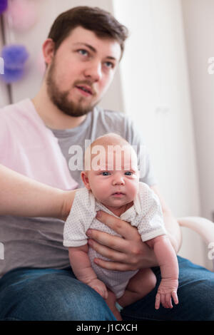 Jeune père de sa fille burping, tenant son affectueusement. Session familiale Lifestyle.. Banque D'Images