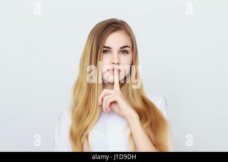 Portrait de jeune femme en gardant le doigt sur ses lèvres et lui demander de se taire Banque D'Images