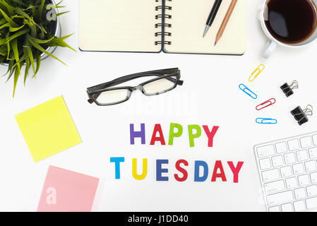Table de bureau avec l'offre, stylo, crayon, ordinateur portable, ordinateur, les lunettes, les Post-it, tasse de café et heureux mardi mot sur fond blanc Banque D'Images