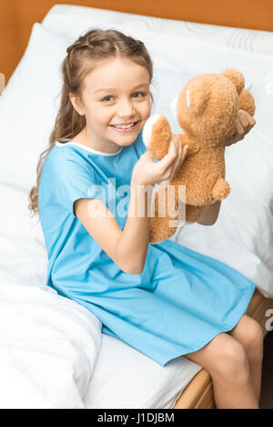 Peu patient avec ours assis sur le lit à l'hôpital Banque D'Images