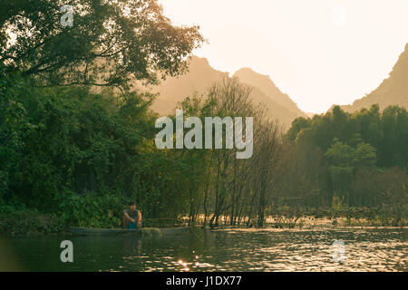 Un pêcheur solitaire travaillant sur la rivière Yen près de la pagode des parfums au coucher du soleil. Vietnam, Asie du sud-est Banque D'Images