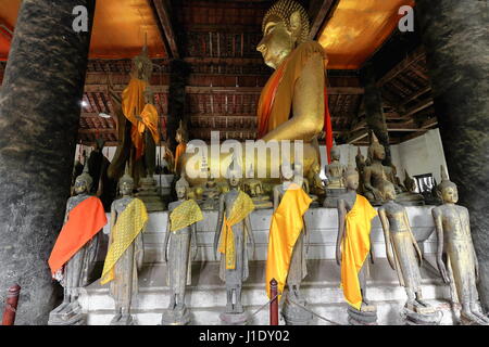 Grande statue de Bouddha Doré entourée par beaucoup de petites figurines en bois et bronze jusqu'à 400 ans dans plusieurs mudras. Sim-congrégation hall of Wat Wisun Banque D'Images