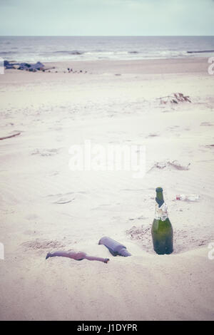 Les tons de couleur photo de bouteilles d'alcool vides laissés sur une plage, la pollution de l'environnement concept photo. Banque D'Images