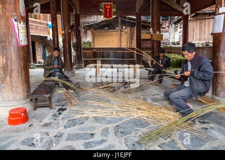 Huanggang, Guizhou, en Chine. Dong Men travaillant, le fractionnement des roseaux, dans une tour du tambour. Banque D'Images