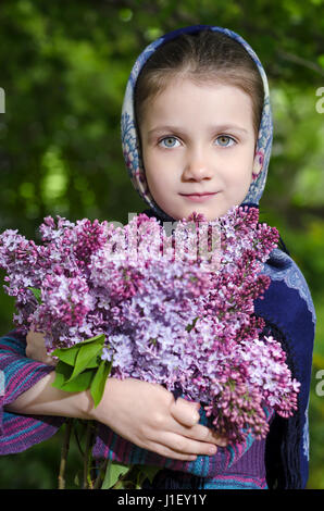 Petite fille avec un bouquet de fleurs en main un lilas Banque D'Images