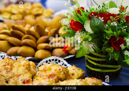 Petites tourtes se situent sur une plaque avec panier de fleurs sur un tableau bleu Banque D'Images