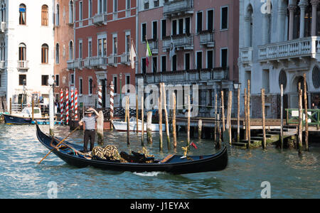 Gondolier holding son chapeau alors qu'il oriente sa gondole à travers le Grand Canal, Venise Banque D'Images
