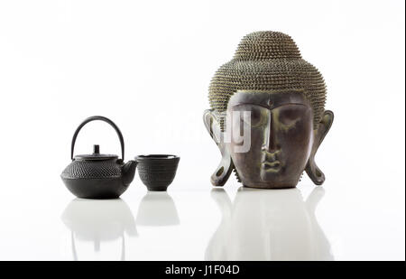 Tête de Bouddha isolé, fer à repasser Fer à repasser théière et tasse sur fond blanc et lotus avec réflexion Banque D'Images