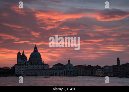 Coucher de soleil sur Venise avec l'église Santa Maria della Salute silhouetté contre le ciel rouge spectaculaire Banque D'Images