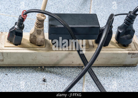 Trop de bouchons dans une douille sale sur le sol. Danger de l'utilisation ancienne douille et trop d'électricité Banque D'Images