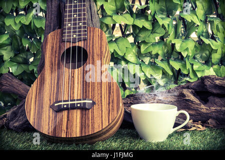 Café chaud avec ukulele sur fond de jardin, style vintage Banque D'Images