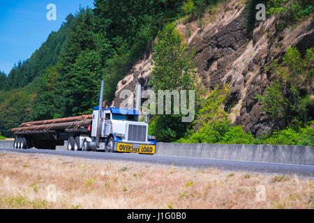 Camion semi classique spectaculaire en combinaison de couleur blanc et bleu avec le signe de la charge surdimensionnée sur bouclier avant transporte des cargaisons surdimensionnées Banque D'Images