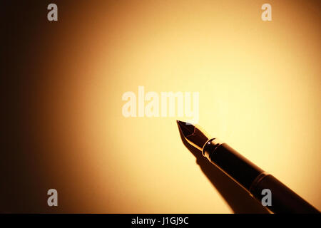Gros plan du stylo élégant sur la surface de papier jaune avec faisceau de lumière Banque D'Images