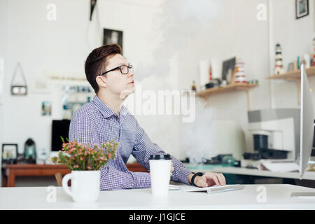 Man in office de fumer avec la cigarette électronique Banque D'Images