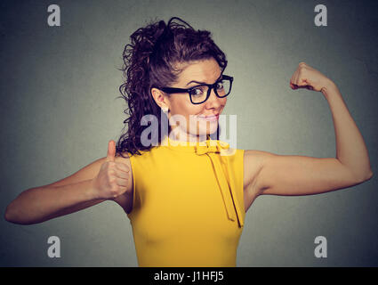 Young happy woman flexing muscles showing Thumbs up isolé sur fond gris. Les émotions positives de l'expression du visage. La perte de poids bien-être concept Banque D'Images