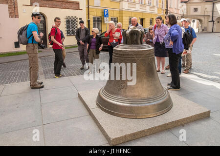 La consultation de groupe touristique la cloche de bronze situé dans la place Kanonia, Vieille Ville, Varsovie, Pologne. Banque D'Images