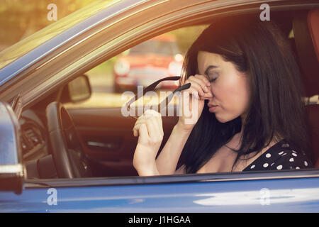 Business Woman having maux de la prise de ses lunettes a de s'arrêter après avoir roulé en voiture embouteillage sur l'heure de pointe. Épuisé, surmené chauffeur c Banque D'Images