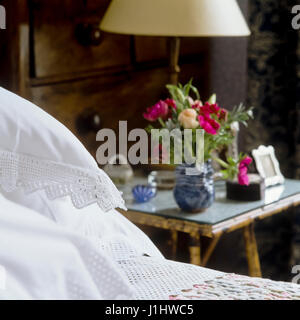 Table de chevet avec lampe et des fleurs. Banque D'Images